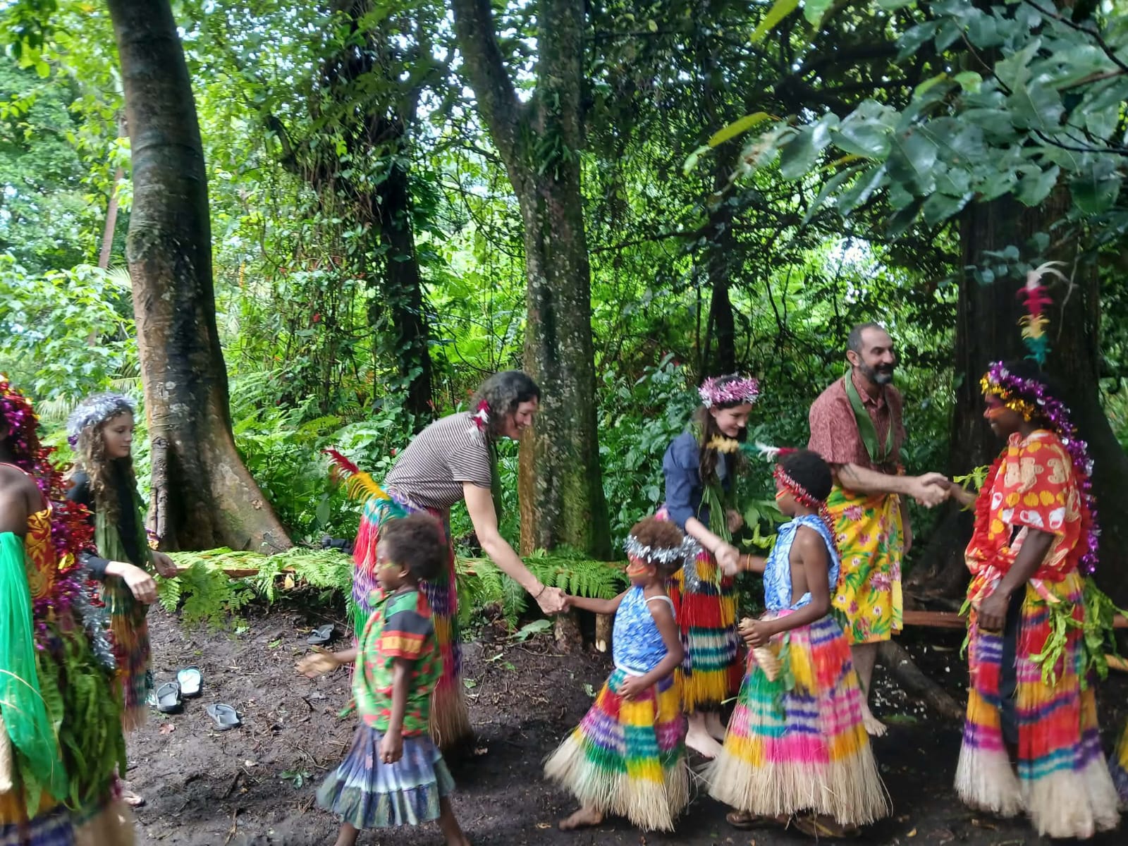 Local children and visiting guests greeting one another in the forest