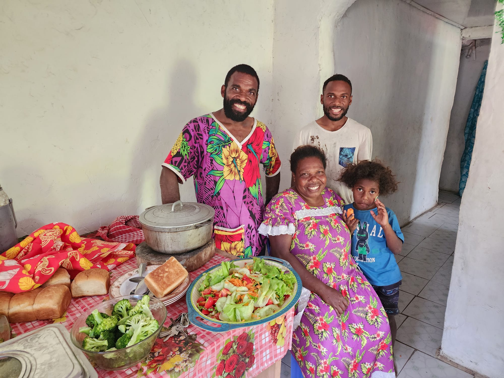 Tehituan hosts smiling beside a freshly prepared shared meal