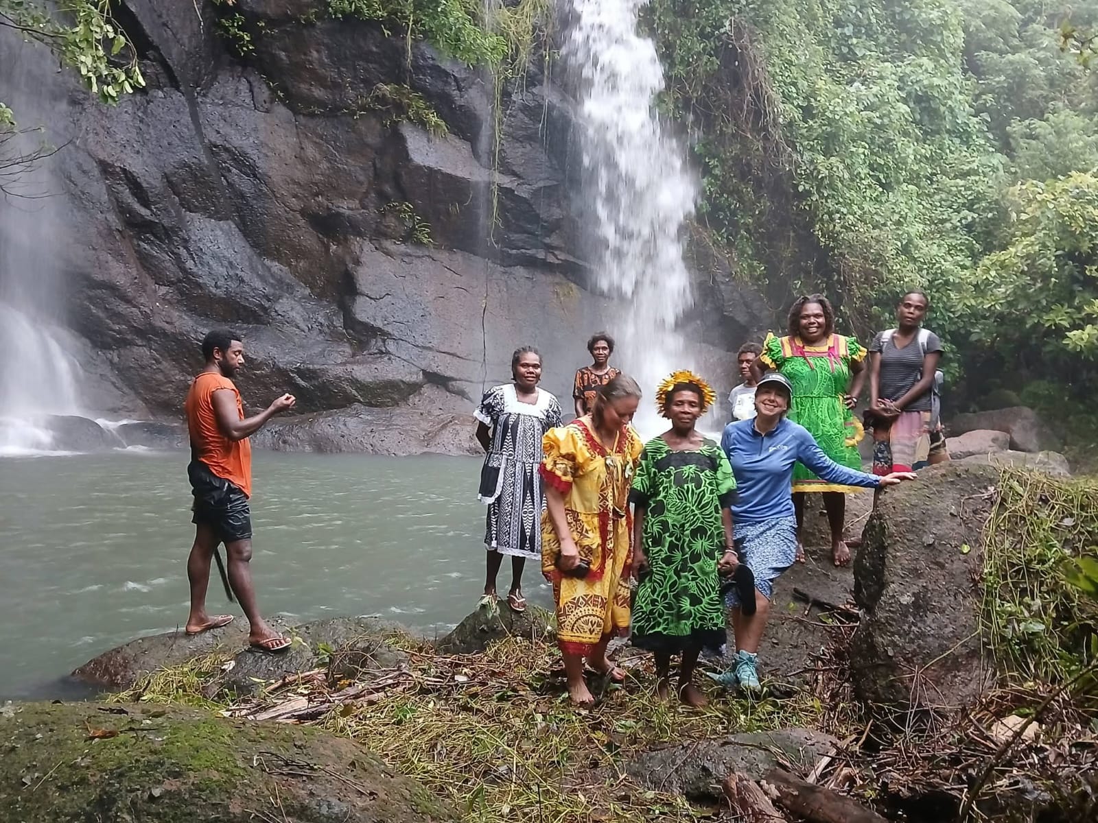 Guests and local guides beside a waterfall